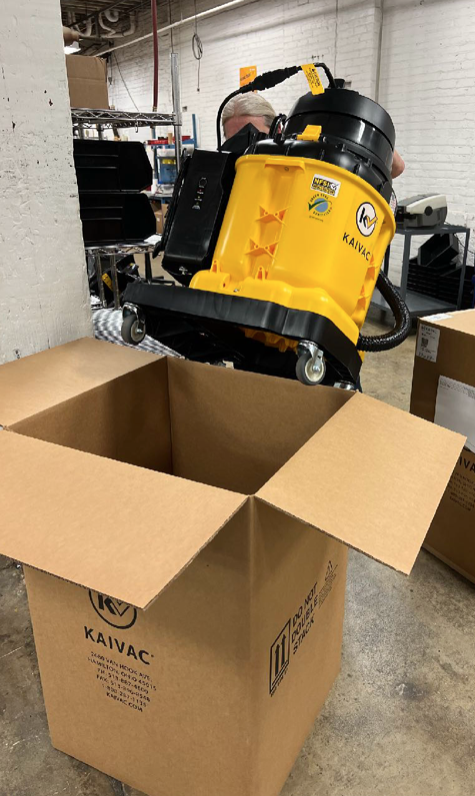 Jenny Myers, Kaivac — before: lifting machines into boxes by hand